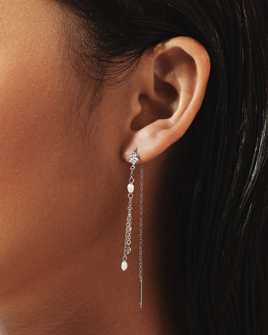 Model wearing Flower Shower Threader Earrings in silver, a plumeria flower swaying below the ear