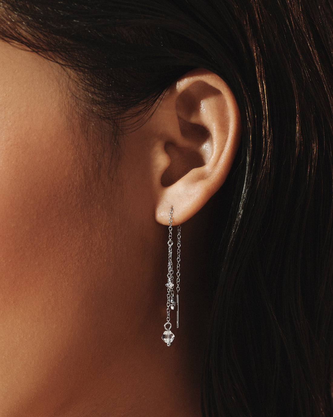Model wearing Sparkle Threader Earrings in silver, a line of crystals falling below the ear