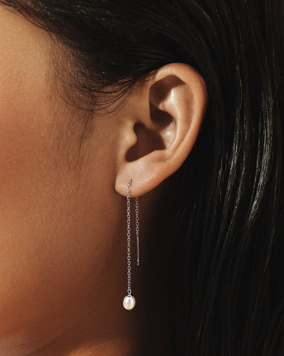 
Model wearing Organic Pearl Threader Earrings in silver, a single freshwater pearl falling below the ear