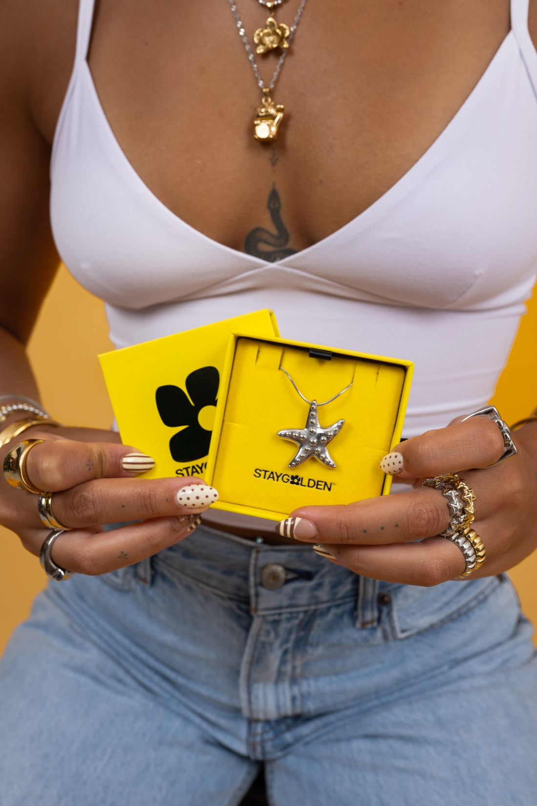Stay Golden necklace in its yellow flip box, held open